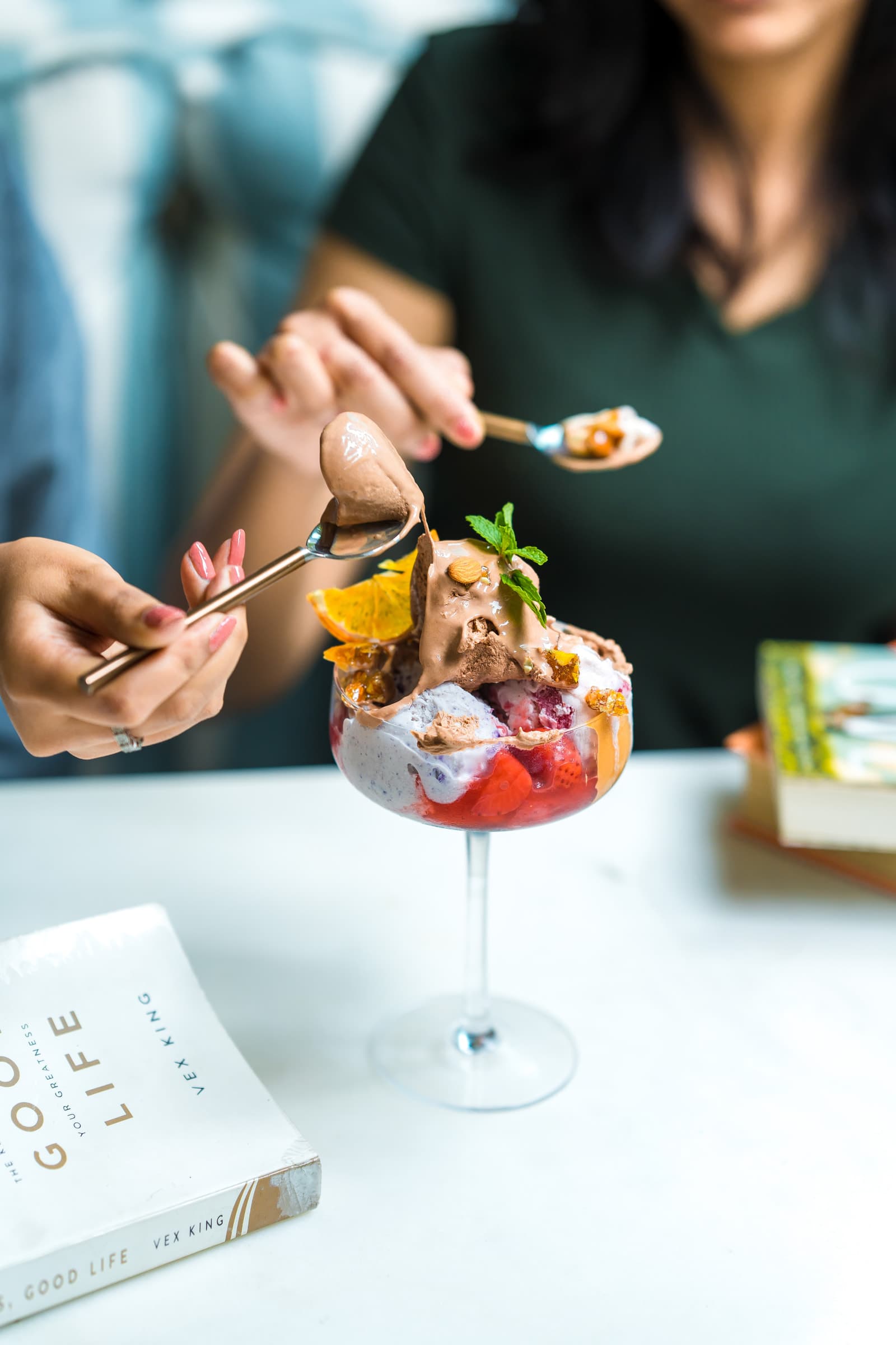 Two guests sharing a layered ice-cream dessert in a coupe glass